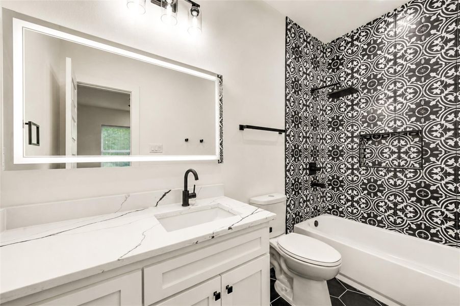 Stylish en-suite for the 2nd bedroom featuring a striking patterned tile wall, sleek white vanity with marble countertop, and modern fixtures.