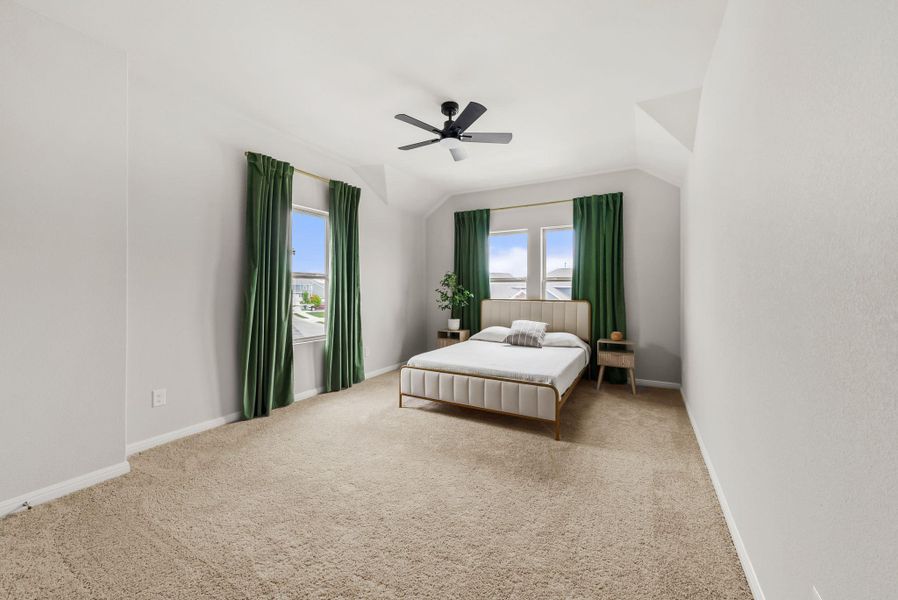 Carpeted bedroom with ceiling fan and lofted ceiling