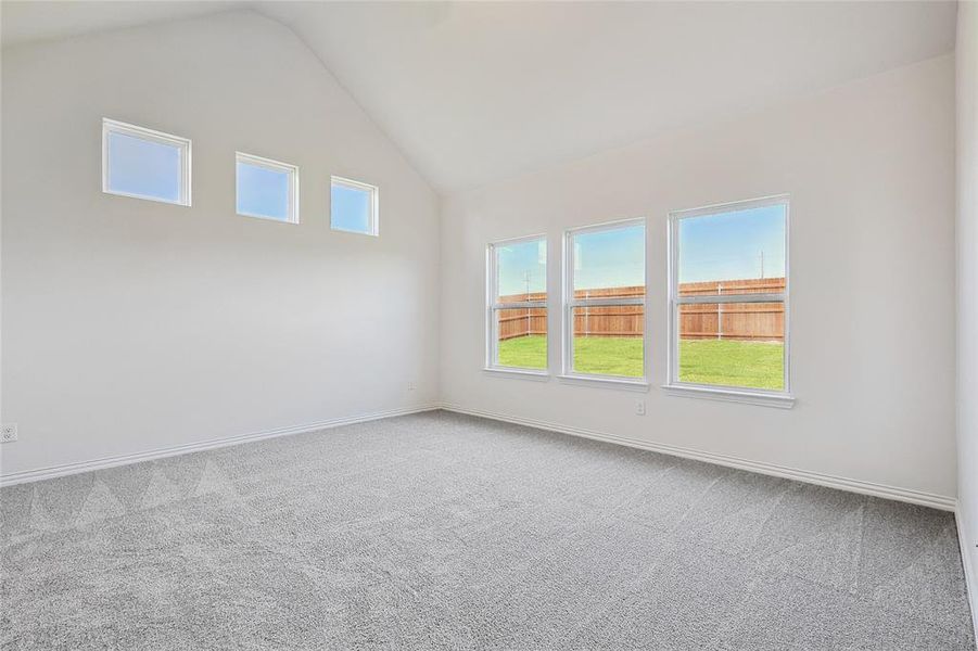 Carpeted empty room featuring lofted ceiling