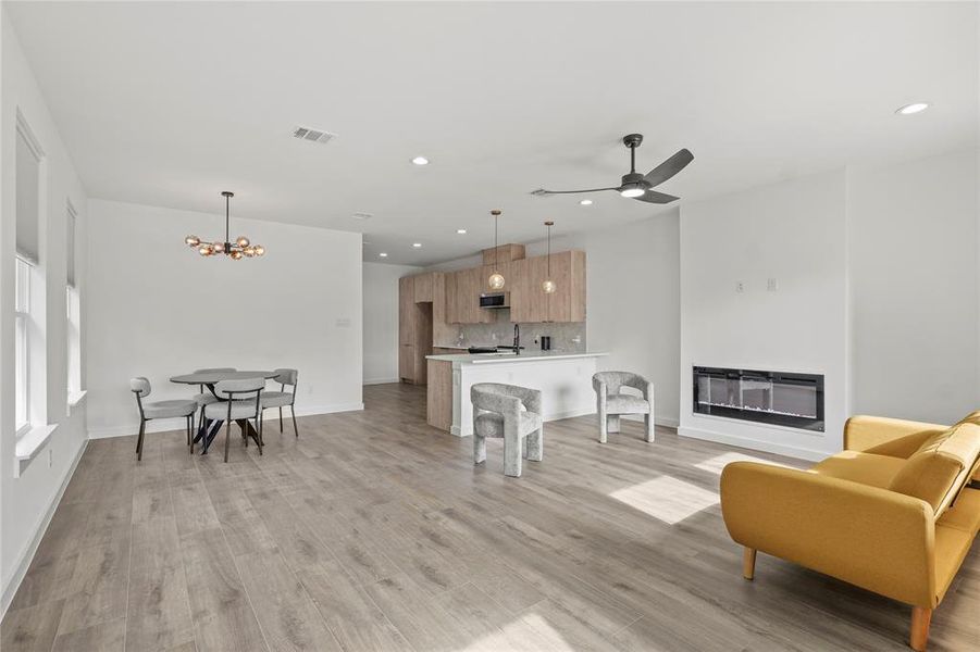 Living room with ceiling fan with notable chandelier, light hardwood / wood-style floors, and heating unit