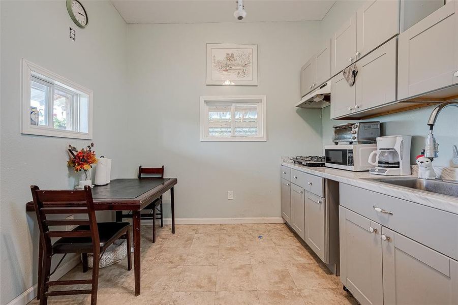 The dining area in front of the kitchen is a cozy and inviting space, featuring a stylish table set amidst tasteful decor, perfect for enjoying meals with family and friends in a relaxed and intimate atmosphere.