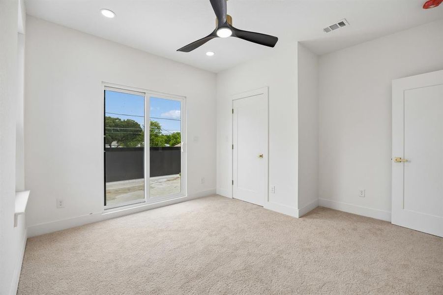 Spacious room featuring neutral carpeting, a modern ceiling fan, recessed lighting, and a large sliding glass door Spacious room featuring neutral carpeting, a modern ceiling fan, recessed lighting, and a large sliding glass door