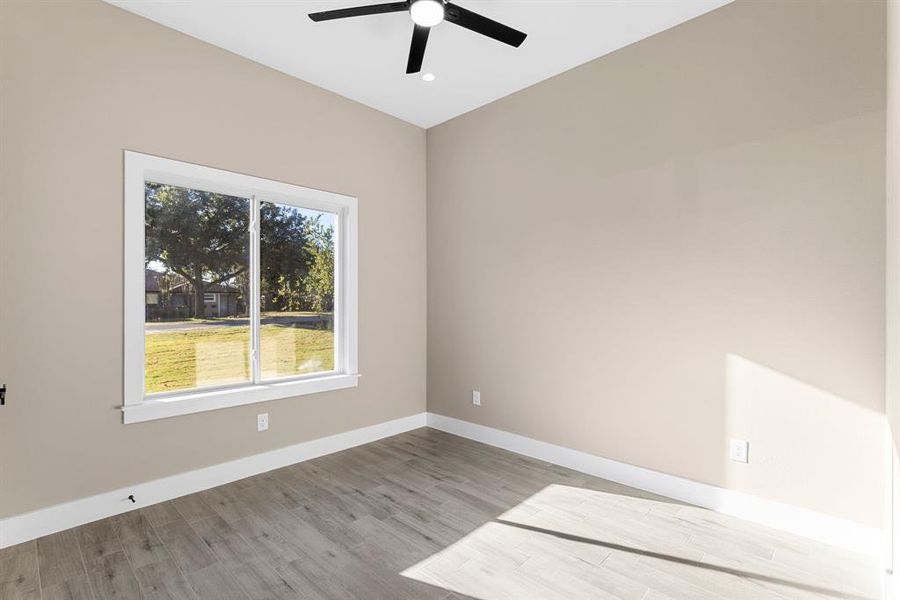 Empty room with ceiling fan and light hardwood / wood-style flooring