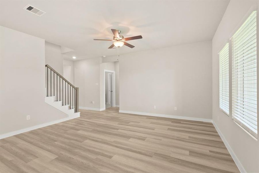 An additional view of the Luxurious Living Room with neutral finishes, ceiling fan for added comfort and staircase to the second floor Flex Space, bedrooms and bathroom.