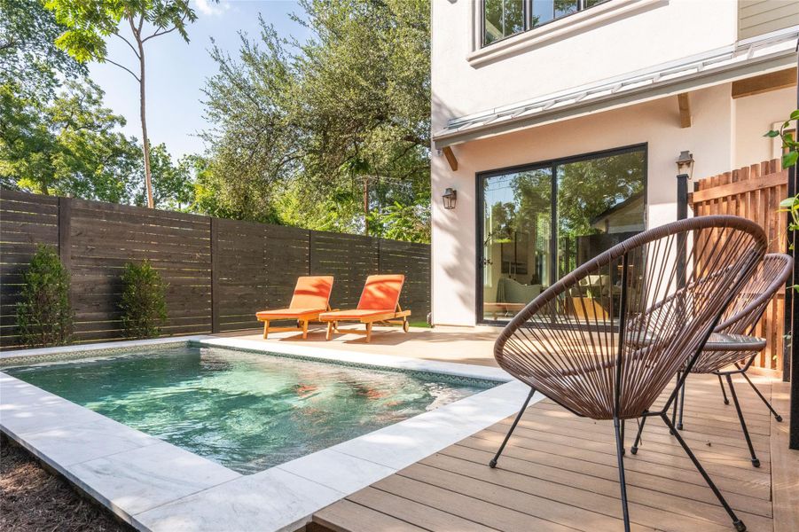 A private backyard oasis features a glistening pool bordered by a sundeck, ideal for serene relaxation.