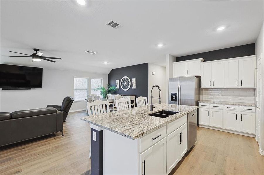 Kitchen featuring white cabinetry, appliances with stainless steel finishes, sink, and an island with sink