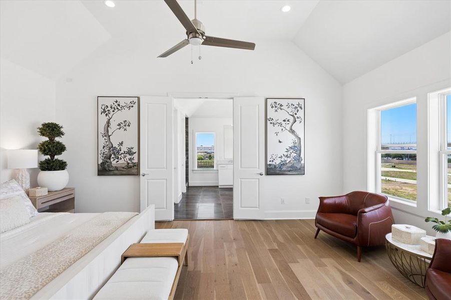 Vaulted ceilings and light wood-finish flooring characterize this room, featuring recessed lighting and a ceiling fan