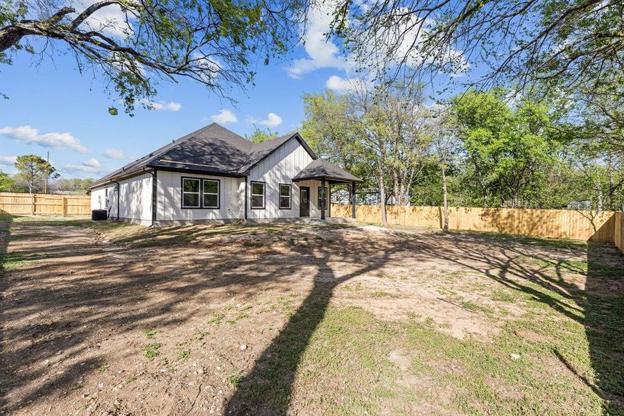 View of front of property featuring a fenced backyard and a shingled roof