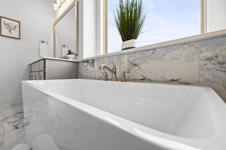 Full bath with a freestanding tub and marble finish floors