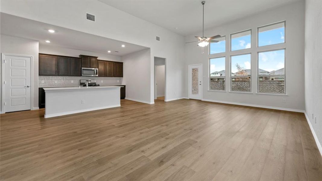 Kitchen with open floor plan, a center island with sink, dark wood finish cabinets, light countertops, and a high ceiling Kitchen with open floor plan, a center island with sink, dark wood finish cabinets, light countertops, and a high ceiling