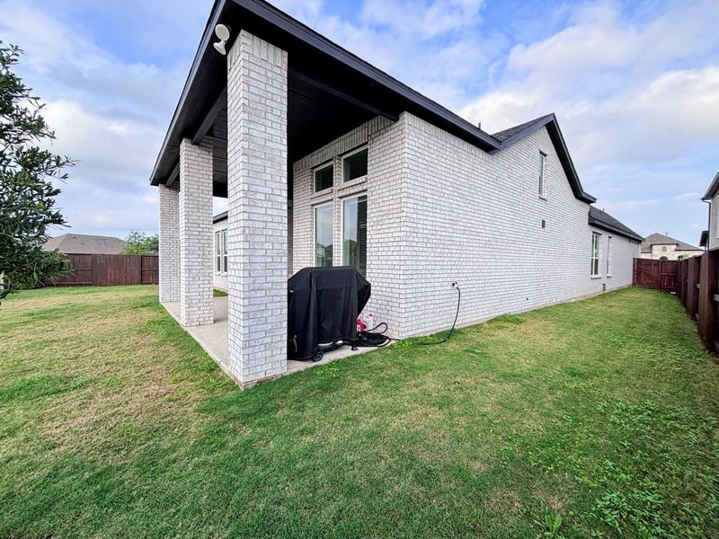 Spacious backyard with a well-maintained lawn and a covered patio area.