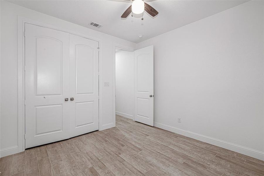 Unfurnished bedroom featuring light wood-type flooring, baseboards, a closet, and ceiling fan Unfurnished bedroom featuring light wood-type flooring, baseboards, a closet, and ceiling fan