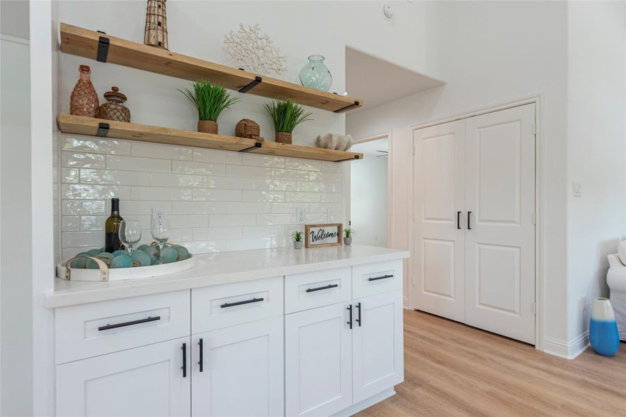 Additional cabinet storage and counter top space with wood shelving and tile backsplash.