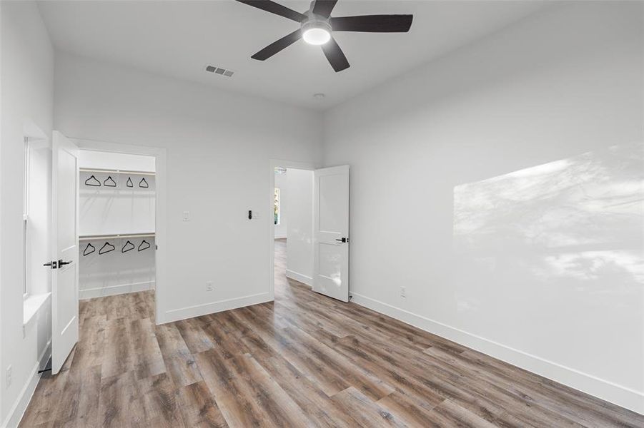 Unfurnished bedroom with a spacious closet, light wood-type flooring, a closet, and ceiling fan