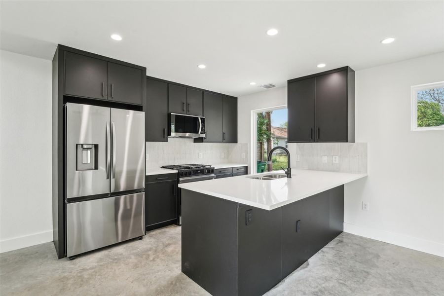 Kitchen featuring appliances with stainless steel finishes, a sink, dark cabinets, backsplash, and recessed lighting