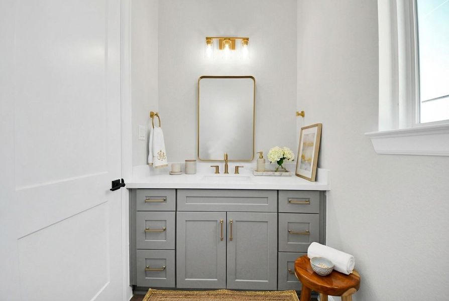 Stylish powder bath on the second floor with quartz countertop, custom vanity, and modern gold fixtures.