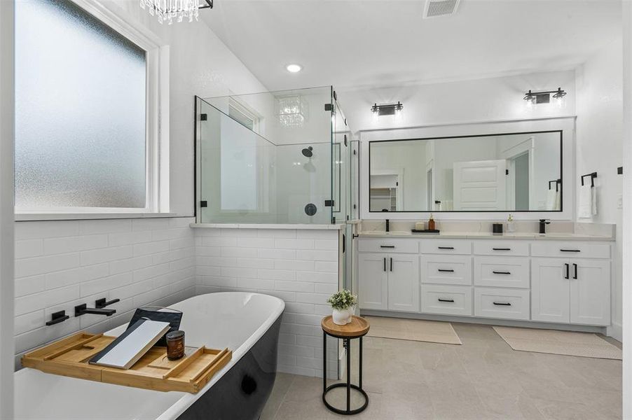 Full bathroom featuring a sink, visible vents, a soaking tub, a shower stall, and double vanity