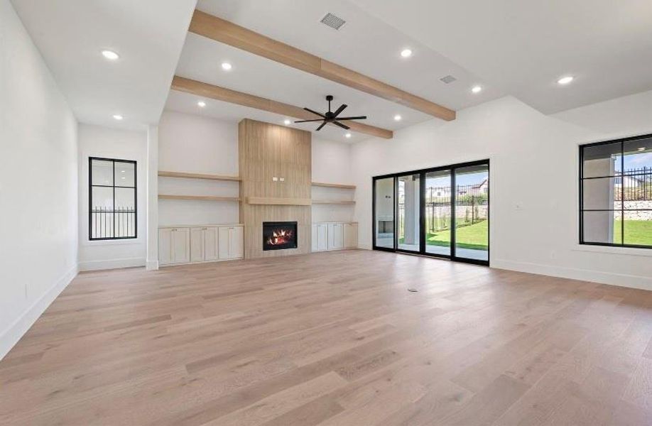 living room with a large fireplace, ceiling fan, light hardwood / wood-style flooring, and beam ceiling