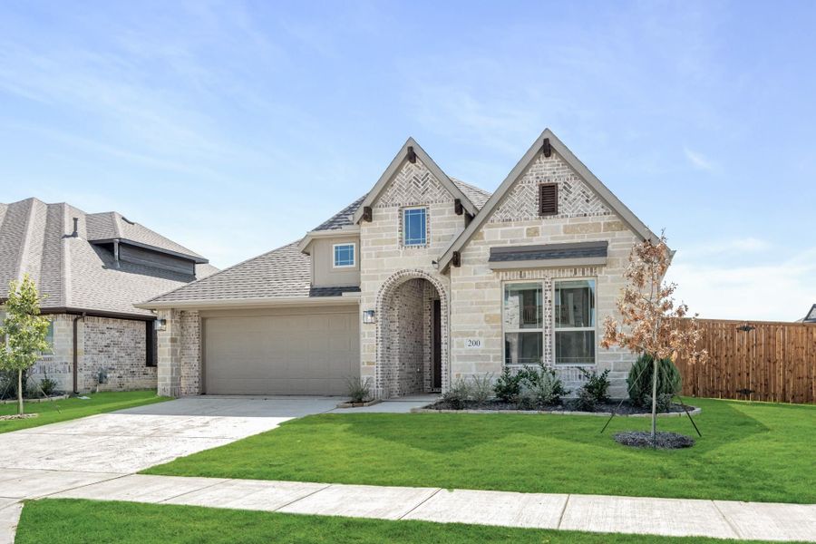 Two-story home with stone and brick exterior, arched entry, two-car garage, and green front lawn. Two-story home with stone and brick exterior, arched entry, two-car garage, and green front lawn.