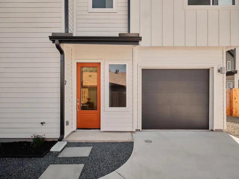 Doorway to property with a garage, concrete driveway, and board and batten siding