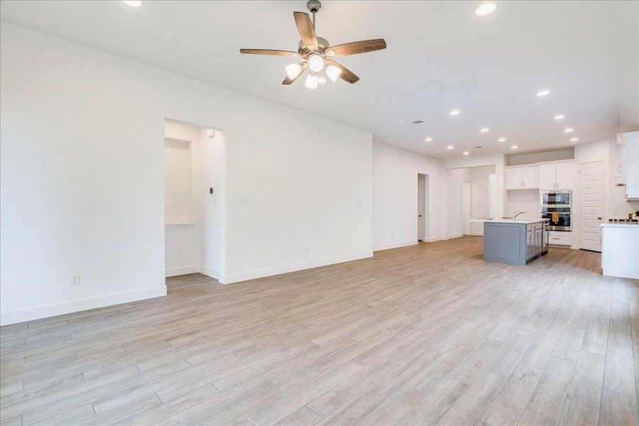 Expansive open-concept living area featuring light-toned flooring, white walls, and recessed lighting