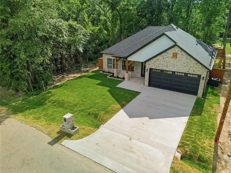 Contemporary single-story residence featuring a light brick exterior, a dark shingled roof, and a two-car garage with a dark sectional door