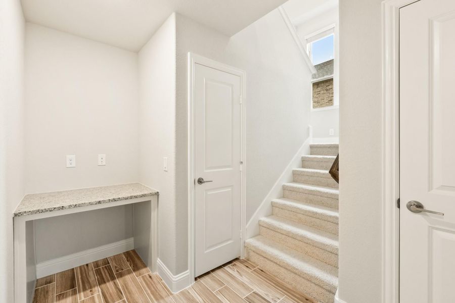 Entryway with built-in granite desk, wood-look tile floors, and carpeted staircase leading to second floor Entryway with built-in granite desk, wood-look tile floors, and carpeted staircase leading to second floor
