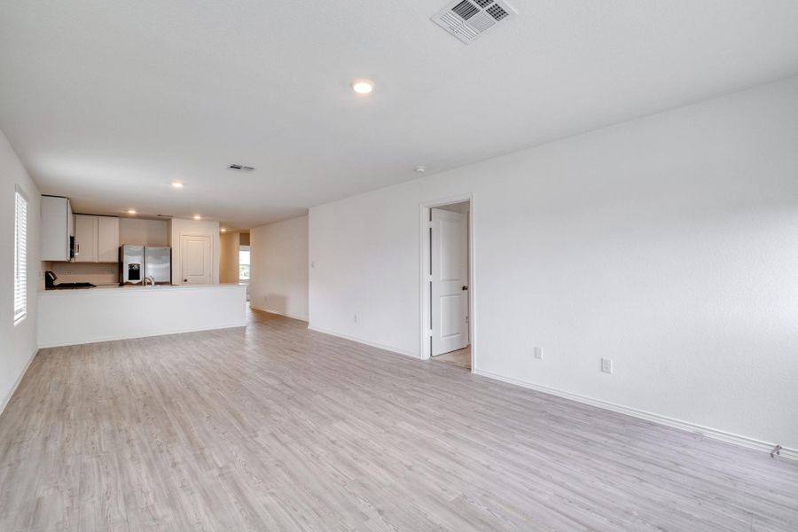 Spacious room featuring wood-finish flooring, recessed lighting, and white walls