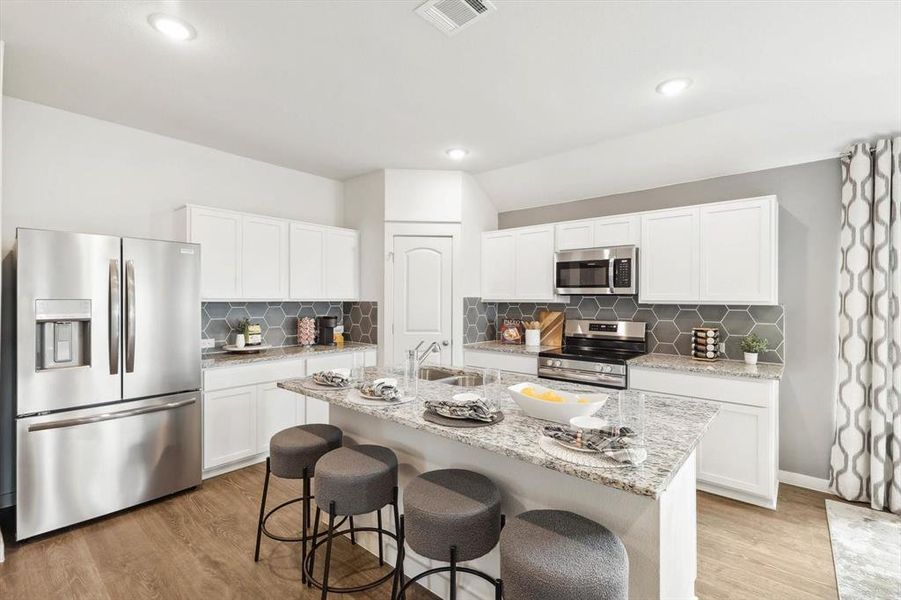 Kitchen featuring light stone countertops, stainless steel appliances, white cabinets, light wood finished floors, and recessed lighting