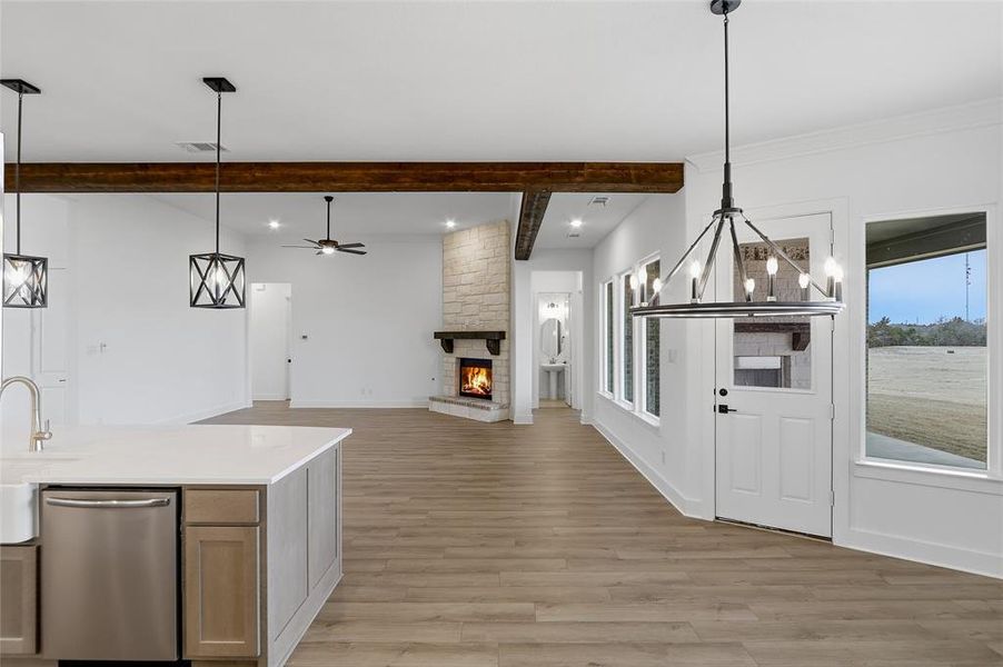 Kitchen with open floor plan, stainless steel dishwasher, a fireplace, light wood finished floors, and a ceiling fan