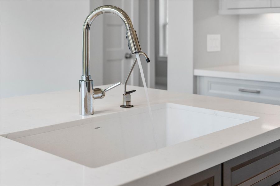 The center-island prep station features a premium, undermount Blanco sink paired with Moen Sleek stainless steel kitchen faucet and filtered water spout. The center-island prep station features a premium, undermount Blanco sink paired with Moen Sleek stainless steel kitchen faucet and filtered water spout.