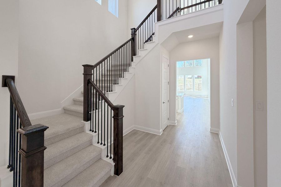 Stairs featuring wood finished floors, recessed lighting, and a high ceiling