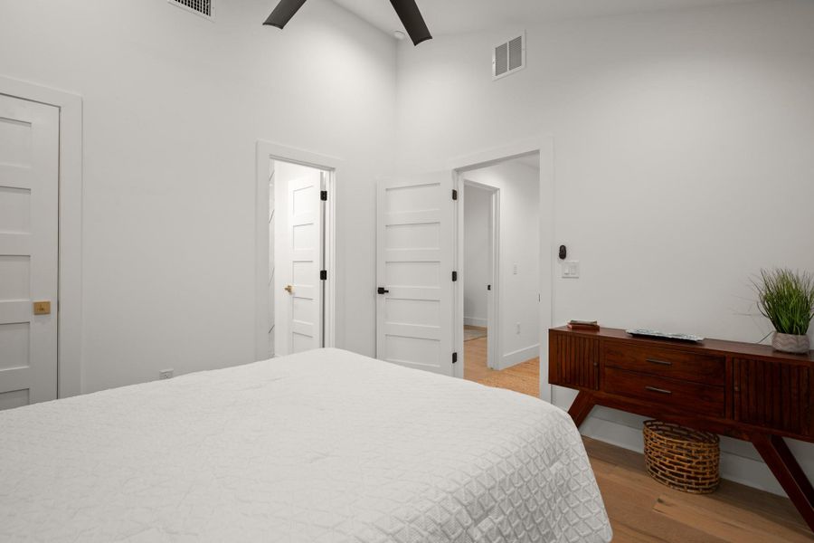 Bedroom featuring light wood-style flooring, a towering ceiling, and a ceiling fan