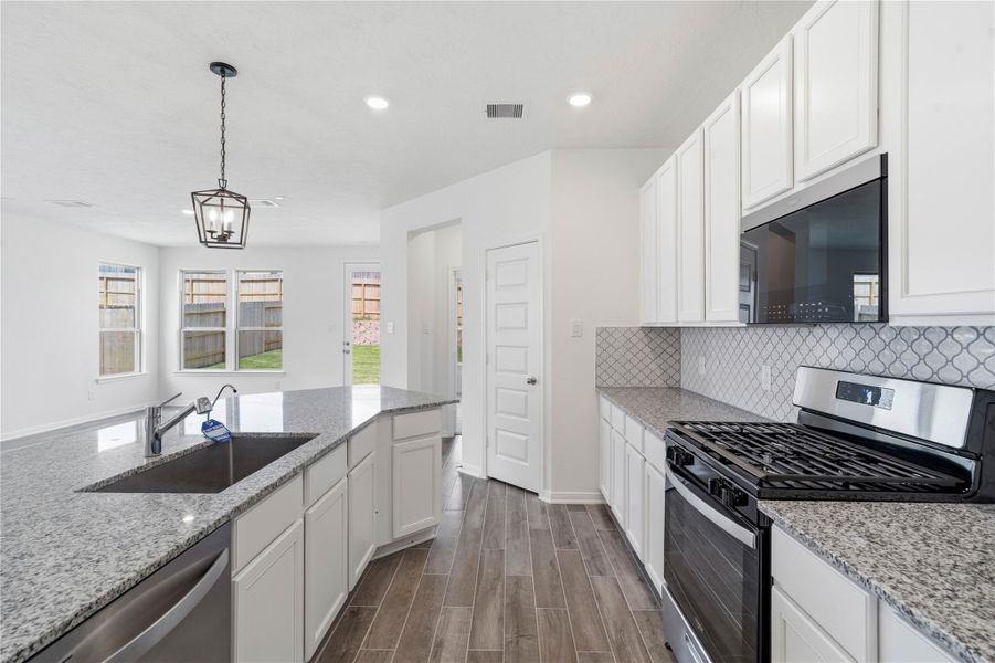 This bright, open kitchen is a chef's delight, complete with a large island, pendant lighting, granite countertops, white Woodmont Dakota cabinets, Whirlpool stainless steel appliances, and modern Daltile backsplash. This bright, open kitchen is a chef's delight, complete with a large island, pendant lighting, granite countertops, white Woodmont Dakota cabinets, Whirlpool stainless steel appliances, and modern Daltile backsplash.