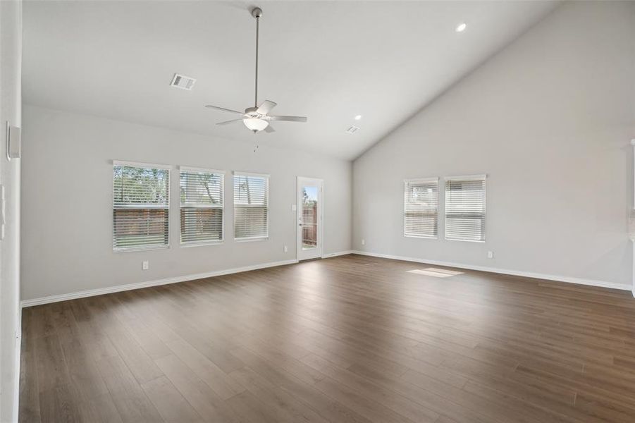 Unfurnished living room featuring ceiling fan, high vaulted ceiling, and dark wood-type flooring