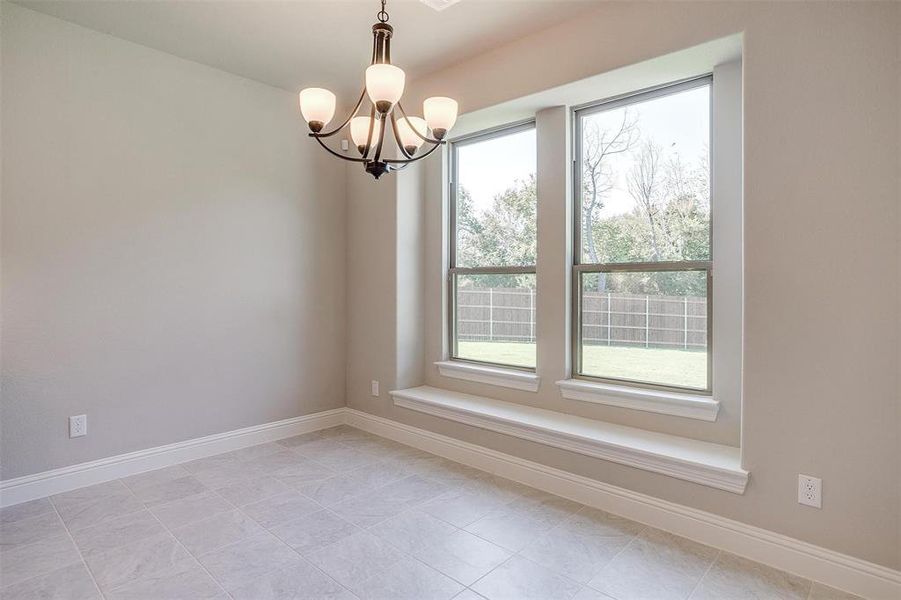 Tiled empty room featuring a chandelier and a healthy amount of sunlight