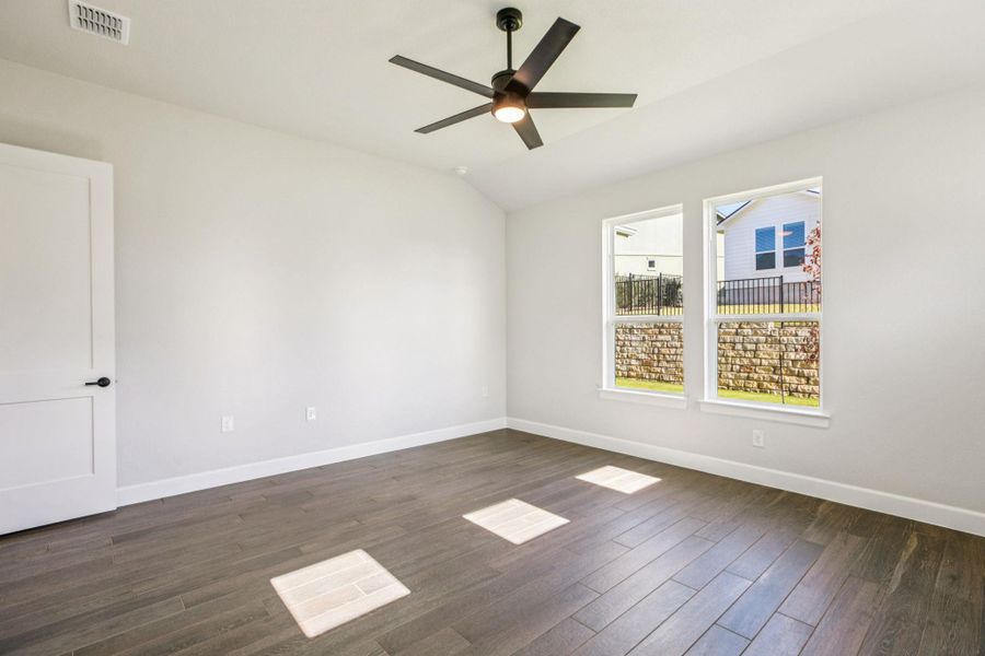 Empty room featuring vaulted ceiling, dark wood-style floors, and a ceiling fan Empty room featuring vaulted ceiling, dark wood-style floors, and a ceiling fan
