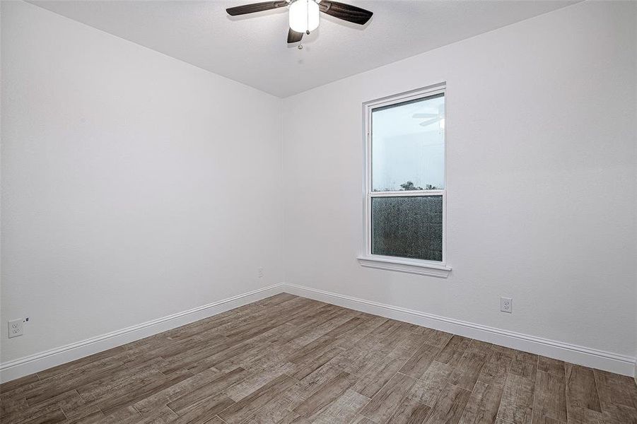Spare room with wood finished floors, a ceiling fan, and baseboards Spare room with wood finished floors, a ceiling fan, and baseboards