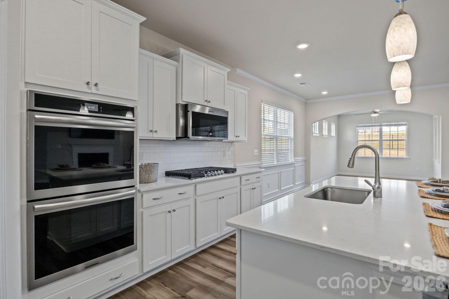 Full view from kitchen to breakfast area with custom moldings, through arched entryway into dining/keeping room.  Notice the clerestory windows which give light yet provide privacy.  Entry door to the fully screened, covered back porch makes entertaining easy!