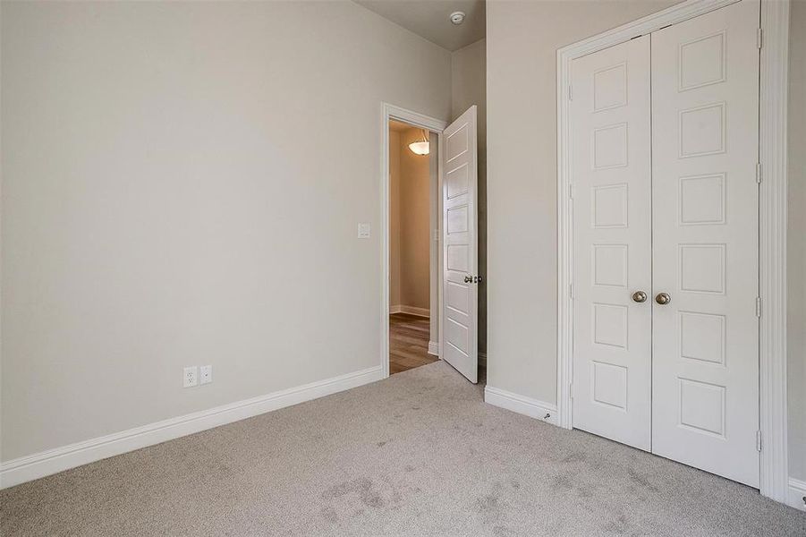 Unfurnished bedroom featuring light carpet and a closet