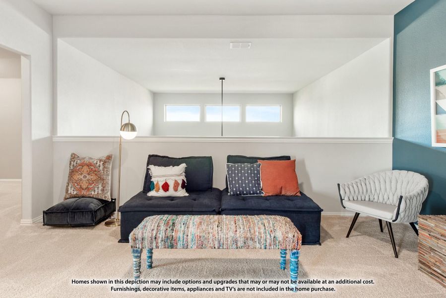 Living room with dark blue sofa, colorful ottoman, and high windows on carpeted floor