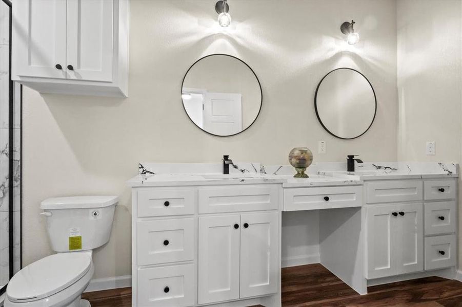 Bathroom with double vanity and dark wood-style flooring Bathroom with double vanity and dark wood-style flooring