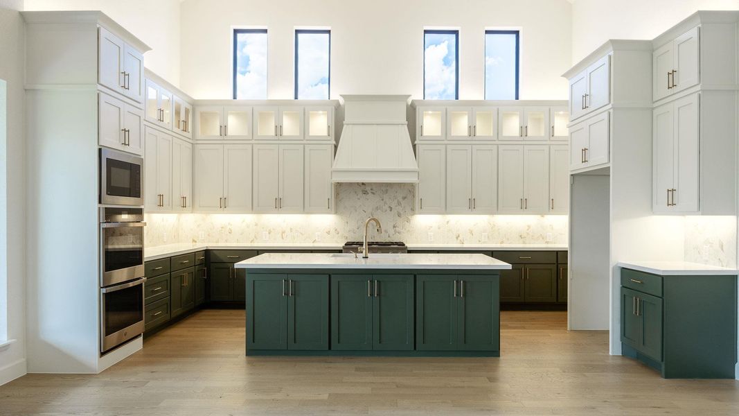 Kitchen with green cabinetry, white cabinets, a center island with sink, healthy amount of natural light, and a high ceiling Kitchen with green cabinetry, white cabinets, a center island with sink, healthy amount of natural light, and a high ceiling