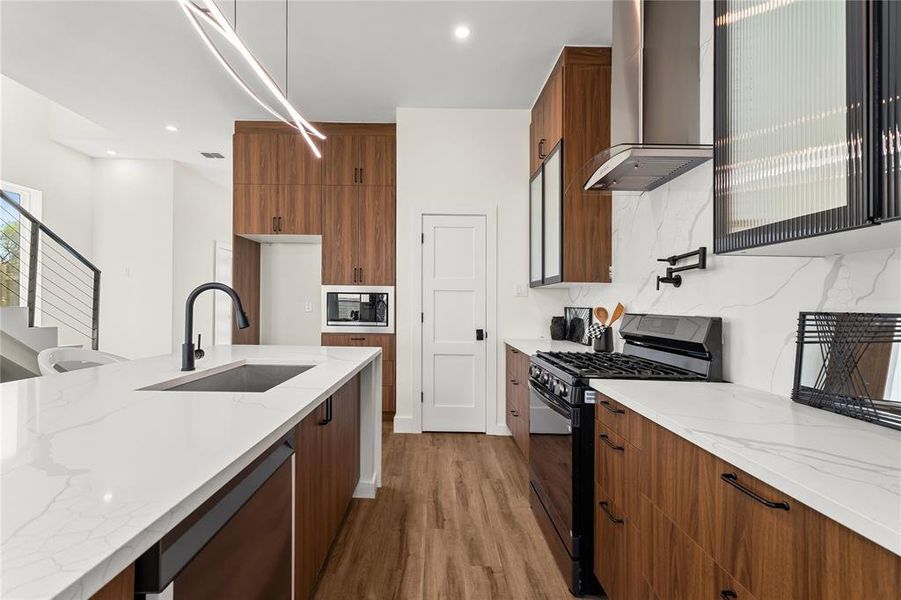 Kitchen with light stone countertops, black appliances, wood finish cabinetry, dark wood-style flooring, and backsplash
