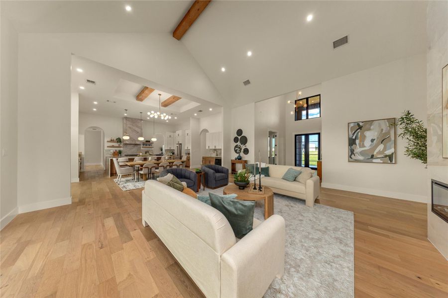 Living area with light wood-type flooring, arched walkways, a chandelier, and lofted ceiling