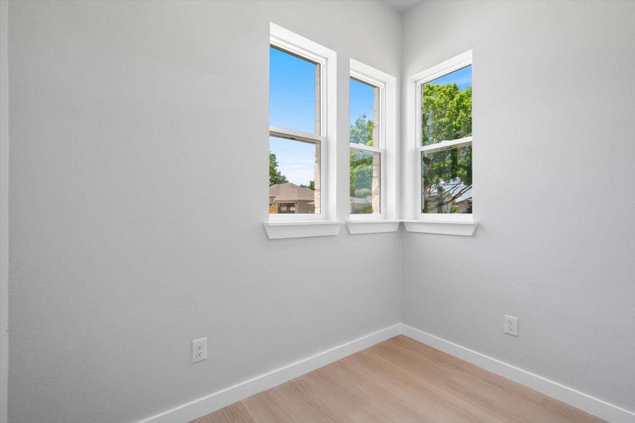 Three casement windows offer ample daylight in this inviting, neutral-toned space.