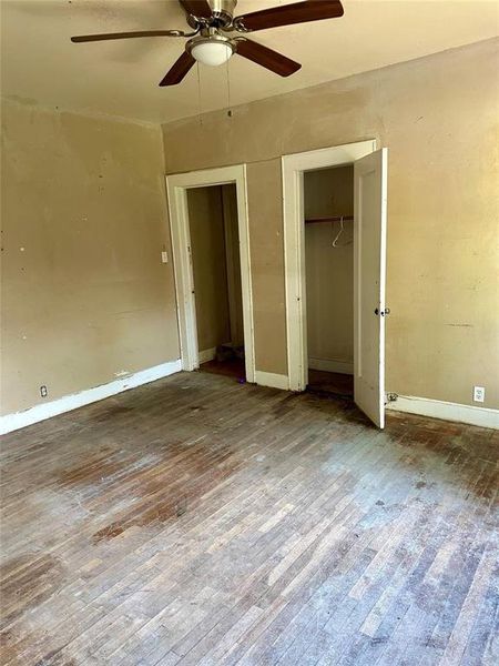 Unfurnished bedroom featuring hardwood / wood-style flooring, a ceiling fan, and two closets Unfurnished bedroom featuring hardwood / wood-style flooring, a ceiling fan, and two closets