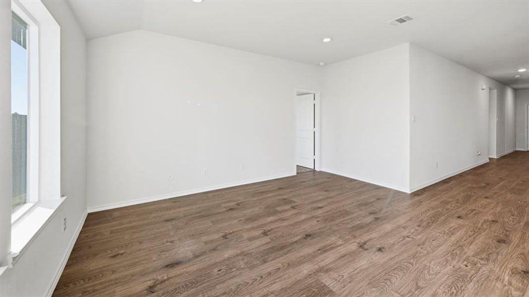 Spare room with plenty of natural light, dark wood-style flooring, recessed lighting, and lofted ceiling
