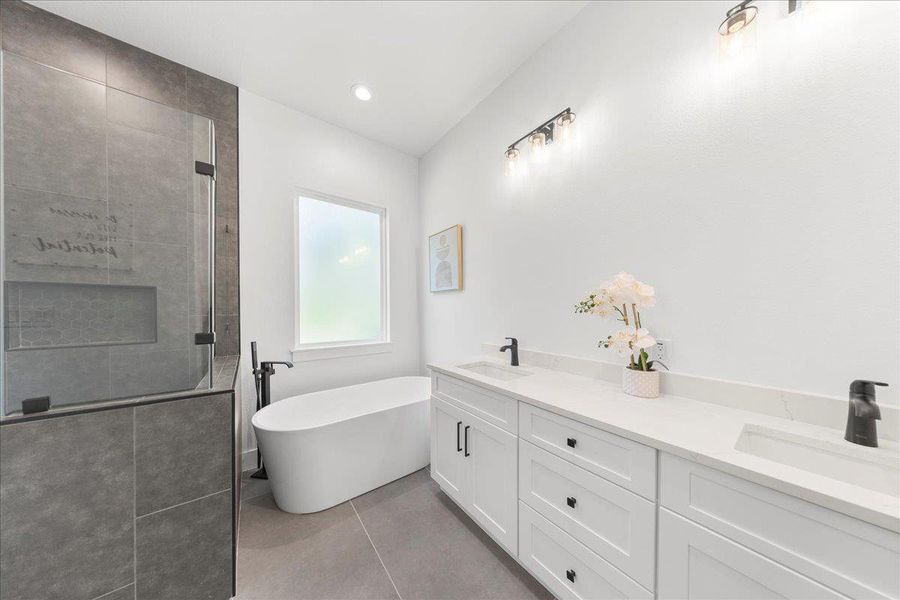 Bathroom featuring a shower stall, a freestanding tub, tile patterned flooring, and double vanity Bathroom featuring a shower stall, a freestanding tub, tile patterned flooring, and double vanity