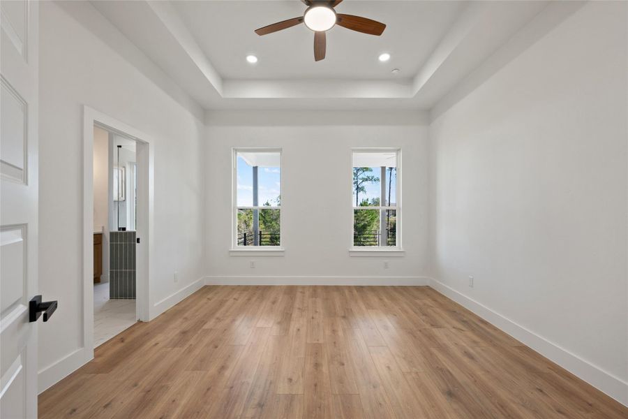 Spare room with light wood finished floors, a tray ceiling, a ceiling fan, and recessed lighting